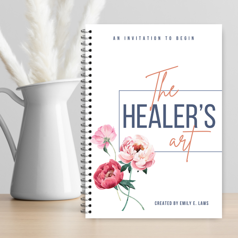The Healer’s Art Workbook next to a white ceramic pitcher filled with pampas grass, emphasizing a minimalist, serene, and nurturing environment.