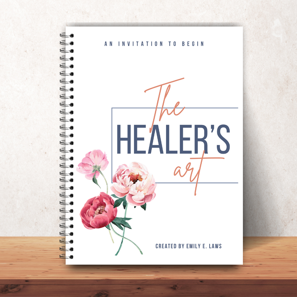 The Healer’s Art Workbook on a smooth wooden surface against a soft beige wall, capturing a warm and inviting tone suitable for personal reflection.