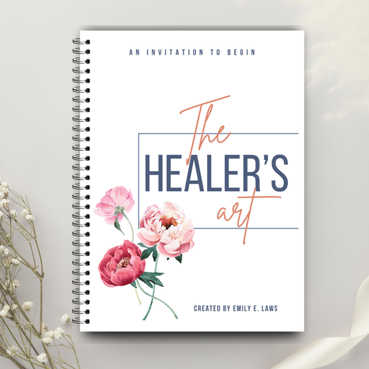 The Healer’s Art Workbook on a light background with delicate white flowers nearby, showcasing a clean, floral cover design and the subtitle “An Invitation to Begin.”
